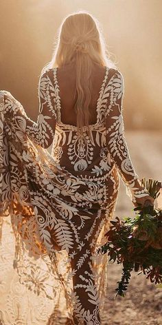 a woman in a white and black dress walking on the beach with her back to the camera