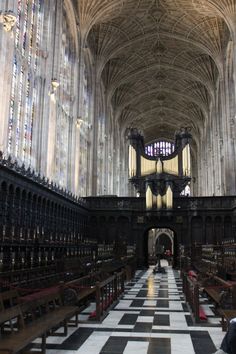 the inside of a large cathedral with pews and stained glass windows on both sides