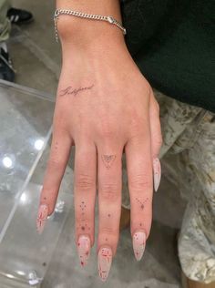 a woman's hand with pink and white nail polishes on her left thumb