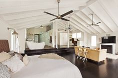 a large white bedroom with wood floors and ceiling fan in the middle of the room