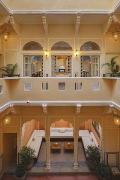 an indoor living area with couches, tables and potted plants in the center