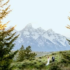 a bride and groom are standing in front of the mountains