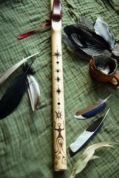 an assortment of different types of feathers on a green cloth with a wooden flute in the middle