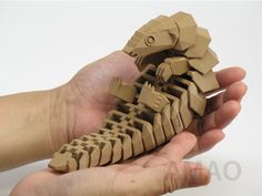 a hand holding a small wooden model of a dinosaur