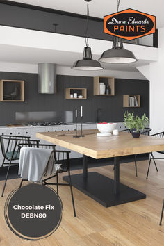 a large wooden table sitting in the middle of a kitchen next to two hanging lights