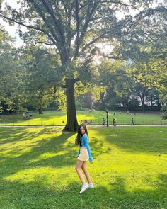 a woman standing in the grass near a tree