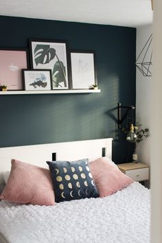 a white bed topped with lots of pillows next to pictures on the wall above it