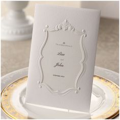 a white wedding card on top of a plate