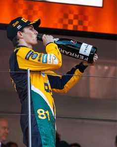 a man drinking from a bottle while standing on top of a race track