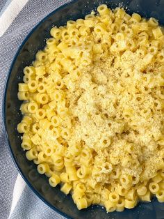 macaroni and cheese in a blue bowl on top of a white table cloth