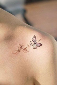 a small butterfly tattoo on the back of a woman's shoulder