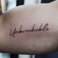 a man's arm with the word unbreekable written on it in cursive font