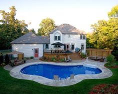 a backyard with a pool, deck and patio furniture in the middle of the yard