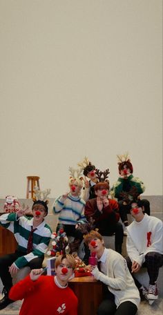 a group of young men sitting next to each other in front of a christmas tree