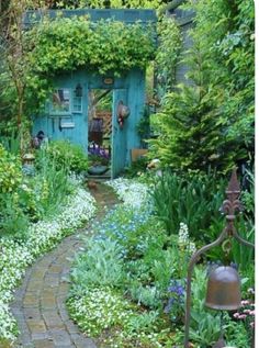 a garden with lots of flowers and plants around it, including an old door in the middle