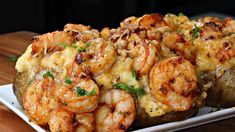 baked potatoes topped with shrimp and cheese on a white plate sitting on a wooden table