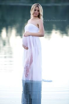 a pregnant woman is standing in the water with her belly wrapped up and looking at the camera