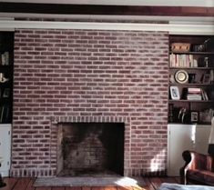 a living room with a brick fireplace and bookshelves