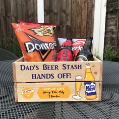 a wooden crate filled with beer, snacks and drinks on top of a metal table