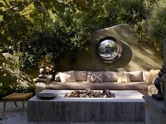 an outdoor living area with couches, tables and mirrors on the wall behind it