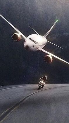 a man riding a motorcycle next to an airplane flying in the sky at night with it's landing gear down