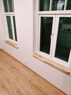 an empty room with wooden floors and two windows on each side of the window sill