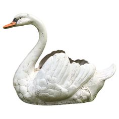 a white swan statue sitting on top of a lush green field