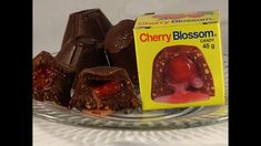 three pieces of cherry blossom candy on a glass plate with a carton of jelly