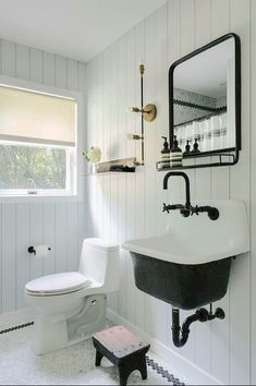 a white toilet sitting next to a black sink in a bathroom under a large mirror