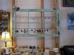 an old window is hanging on the wall above a table full of earrings and bracelets