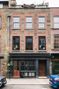 two cars are parked in front of an old brick building with many windows and doors