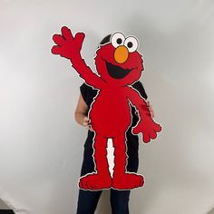 a woman holding up a cut out of an elm street character from the sesame series