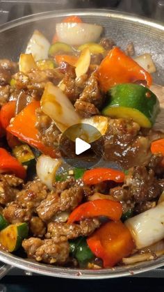 a pan filled with meat and veggies on top of a stove burner