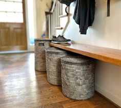 two baskets are sitting on the floor next to a bench and coat rack with shoes hanging from it