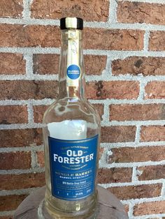 an old forester bottle sitting on top of a tree stump in front of a brick wall