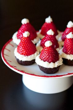 a plate topped with cupcakes covered in whipped cream and strawberries on top