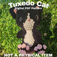 a black and white stuffed animal sitting on top of a lush green field with the words tuxedo cat written below it