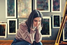 a woman sitting on the floor in front of a painting