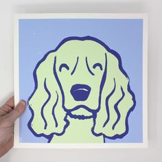 a hand is holding up a blue and green print with a dog's face