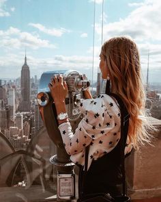 a woman looking through a telescope at the city