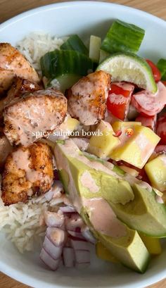 a white bowl filled with meat, rice and veggies on top of a wooden table