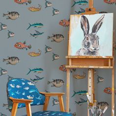 an easel with a painting of a rabbit on it next to a chair and fish wallpaper