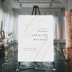 a welcome sign in front of a wedding ceremony backdrop with candles on the floor and lights behind it