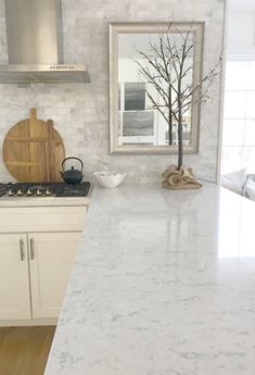 a kitchen with white marble counter tops and wooden cutting board on the stove top next to an oven