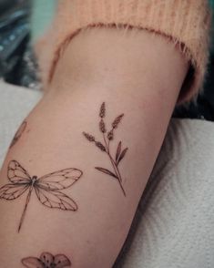 a woman's arm with dragonflies and flowers on it