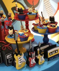 cupcakes with guitars and other musical instruments on them are displayed in front of a backdrop