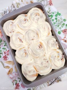 a pan filled with food sitting on top of a floral table cloth next to a napkin