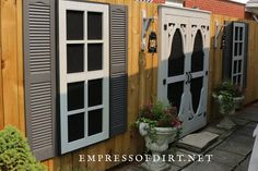 the side of a house with shutters and potted plants