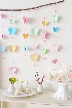 a table topped with lots of white vases filled with flowers and paper butterflies hanging from the ceiling