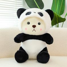 a stuffed panda bear sitting on top of a couch next to a potted plant